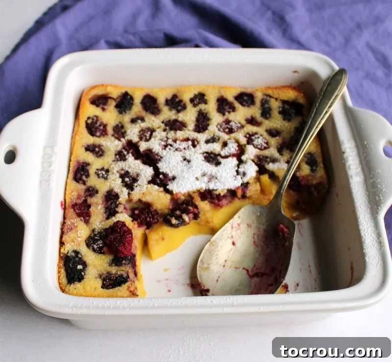 Vintage Spoon in Blackberry Clafoutis Vintage berry spoon resting in a pan of custardy clafoutis, generously dotted with ripe blackberries.