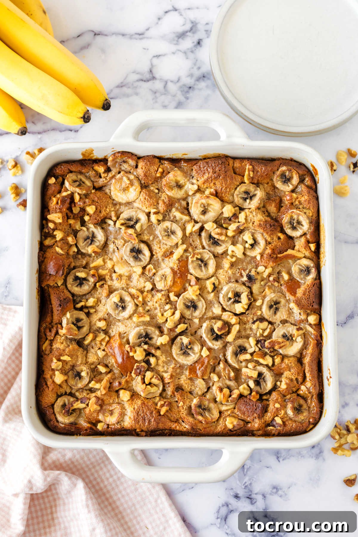 A freshly baked pan of banana bread pudding, showcasing its beautiful golden-brown, slightly crispy top, a clear indicator that it's perfectly cooked, set, and ready to be served and enjoyed.