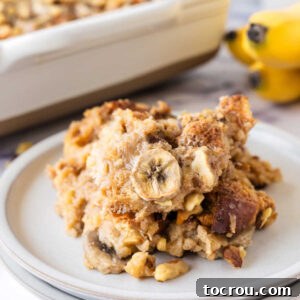 Close up serving of banana bread pudding with slices of bananas and chopped walnuts.