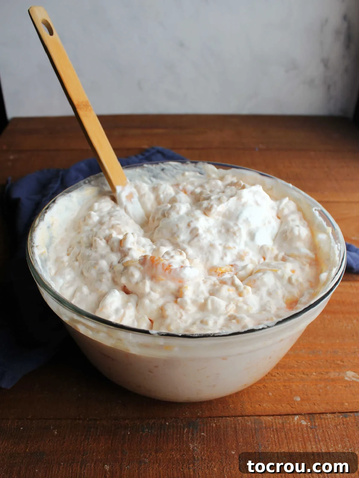 Large mixing bowl filled with orange jello salad with cottage cheese, ready to go in the fridge to chill for a couple of hours.