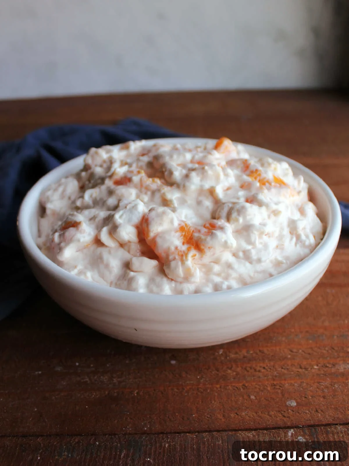 Serving bowl with orange cottage cheese jello salad with chunks of mandarin orange showing.