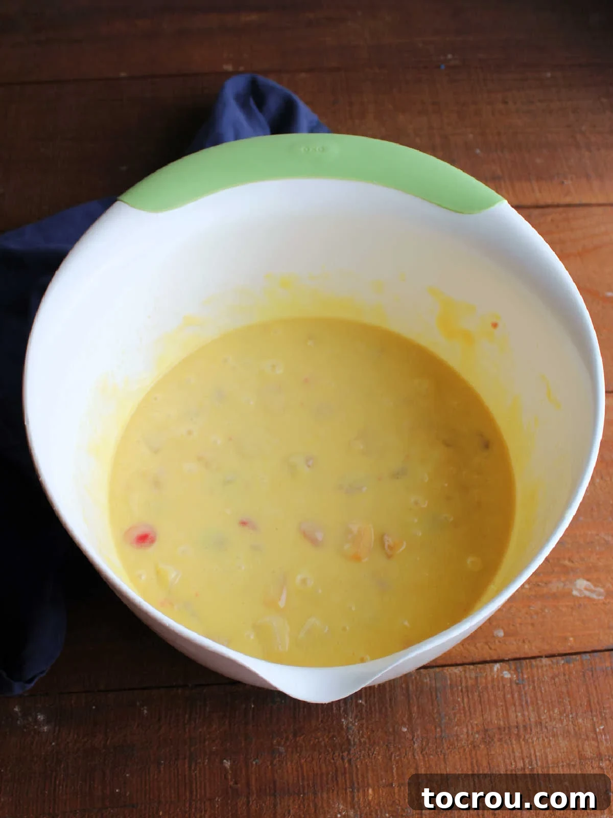 A mixing bowl filled with a perfectly combined fruit cocktail cake batter, smooth and ready for baking, showcasing the vibrant fruit pieces incorporated throughout.