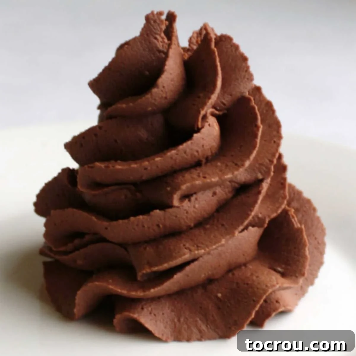 Swirl of super chocolaty, darker in color chocolate buttercream frosting, ready to be spread.