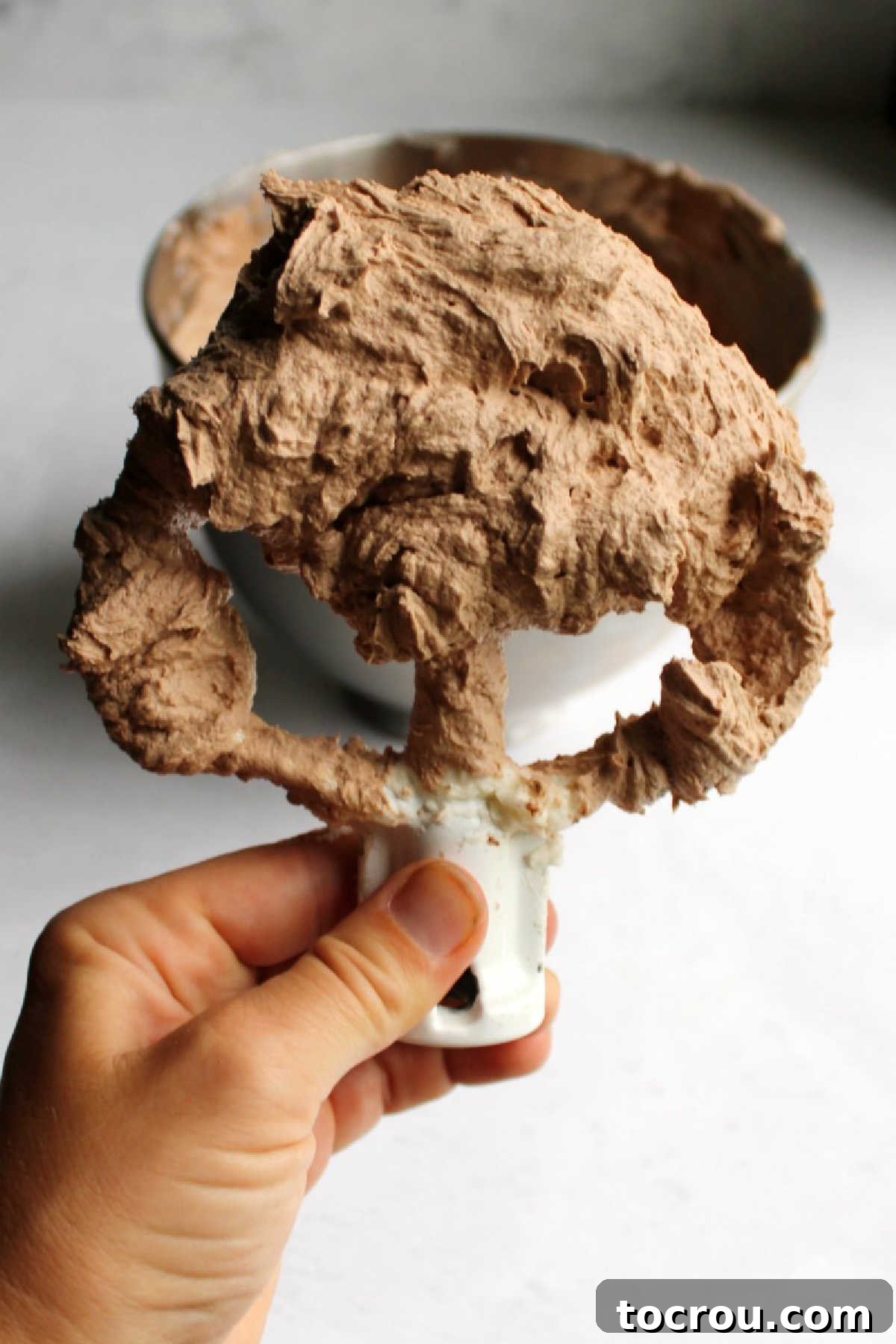 Lighter chocolate buttercream on a mixer paddle, showcasing a smooth, creamy texture.