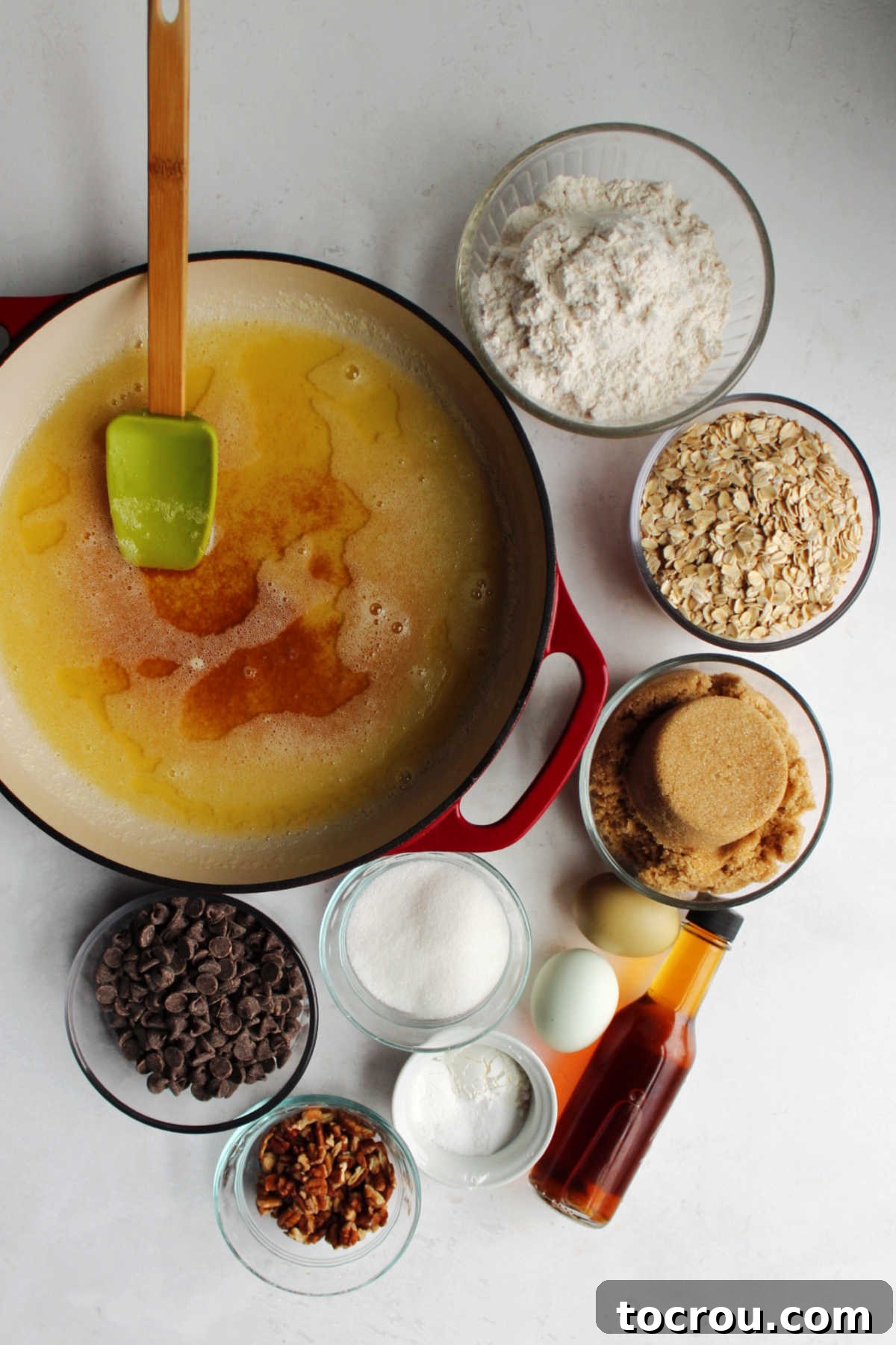 Ingredients including brown butter, flour, oatmeal, brown sugar, sugar, baking soda, baking powder, corn starch, vanilla, eggs, pecans, and chocolate chips ready to be made into cowgirl cookies.