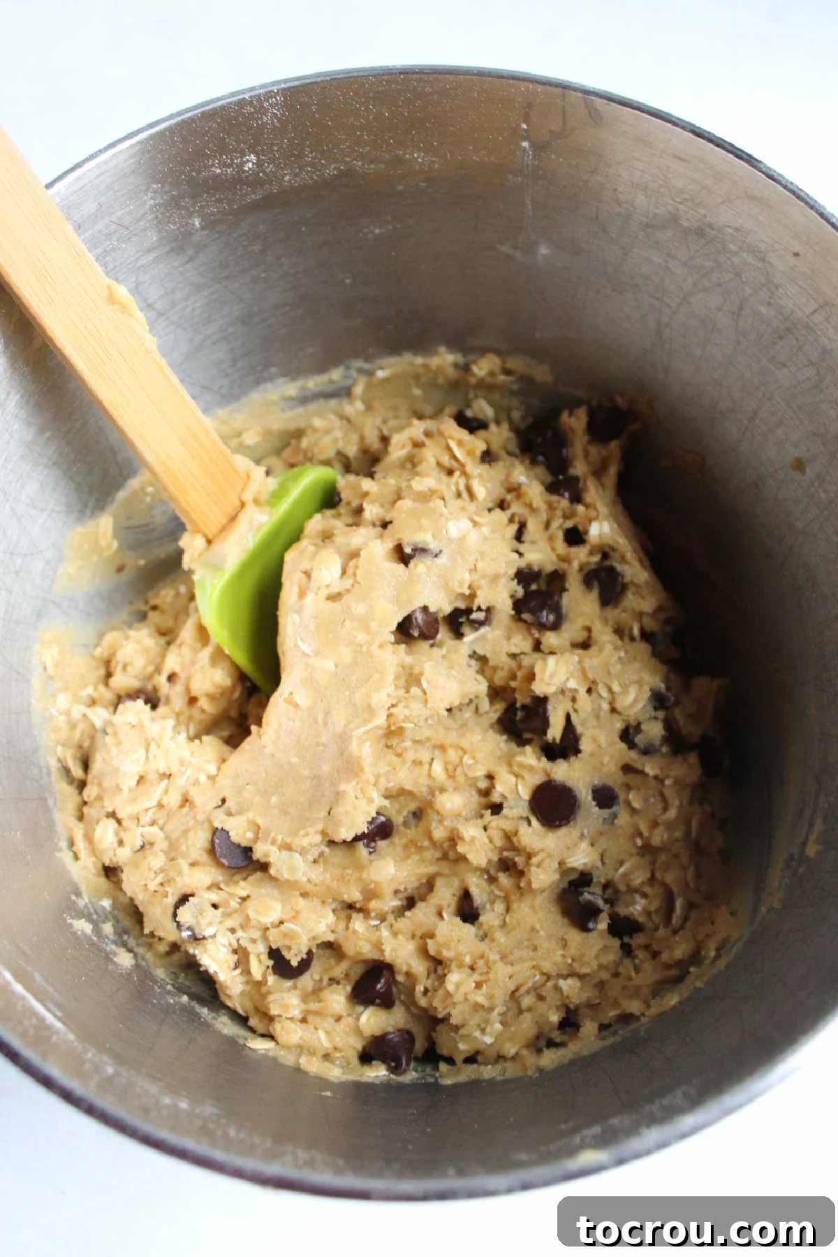 Mixer bowl filled with cowgirl cookie dough with oats and chocolate chips.