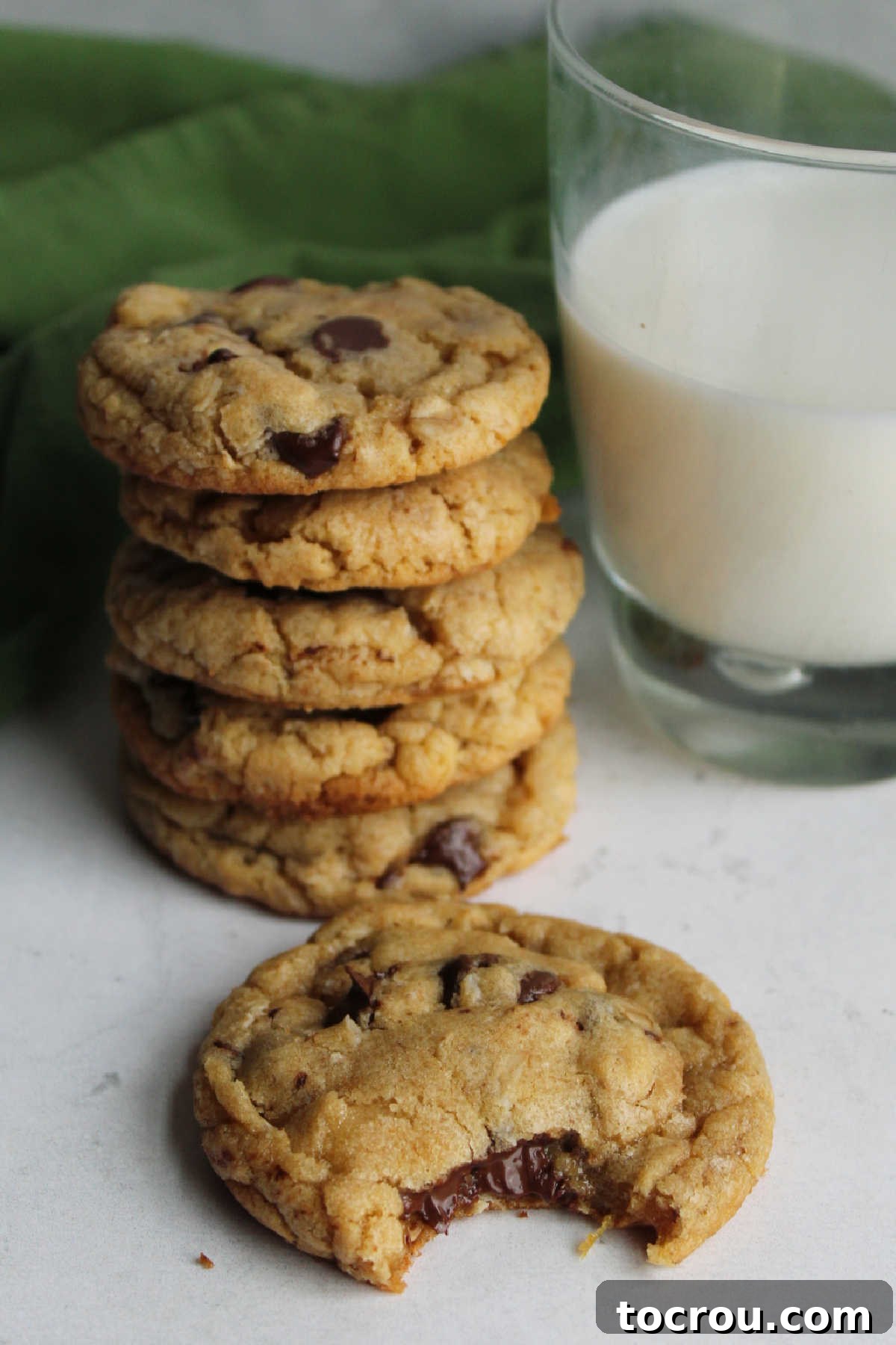 Bite missing from warm cowgirl cookie showing melted chocolate chips and gooey center.
