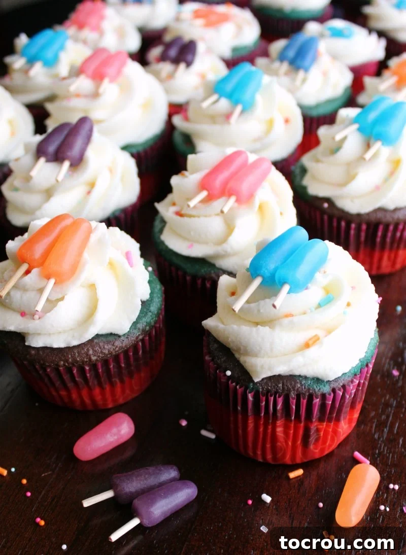 A group of sweet summertime cupcakes with extra sprinkles and several Mike and Ike candies scattered in the foreground, creating a festive display.
