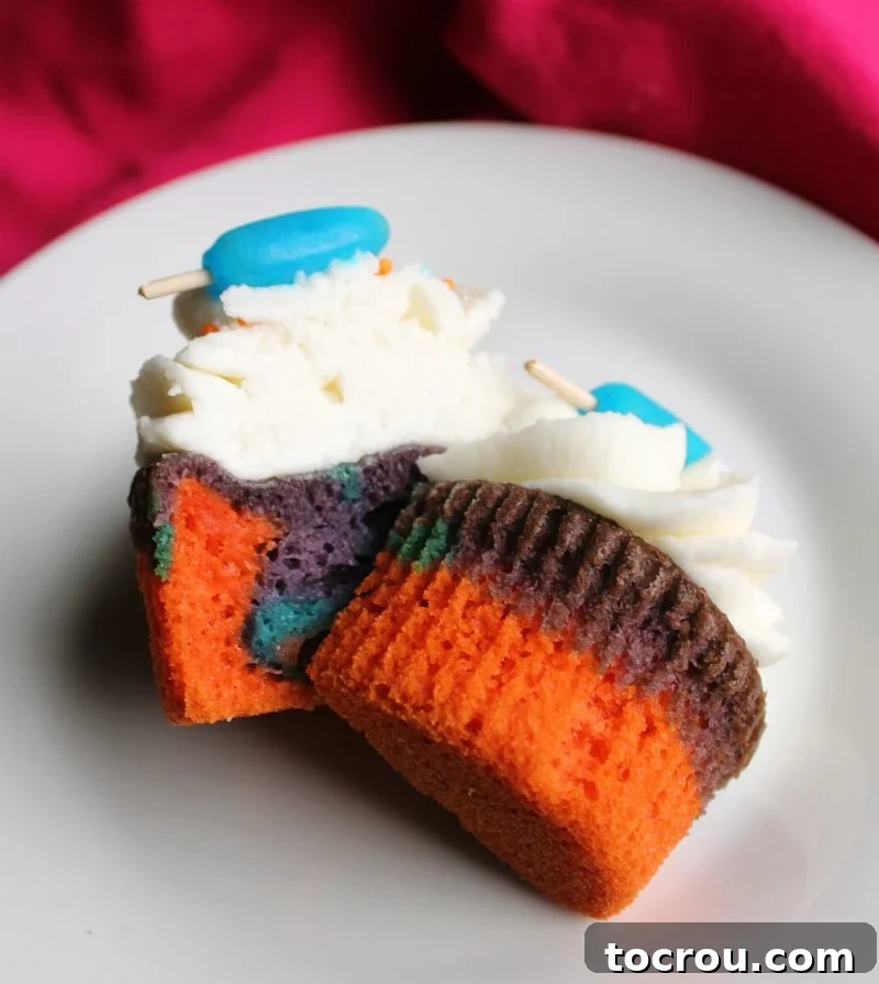 A colorful summertime cupcake sliced open to reveal the beautiful pink, blue, and purple layers inside.