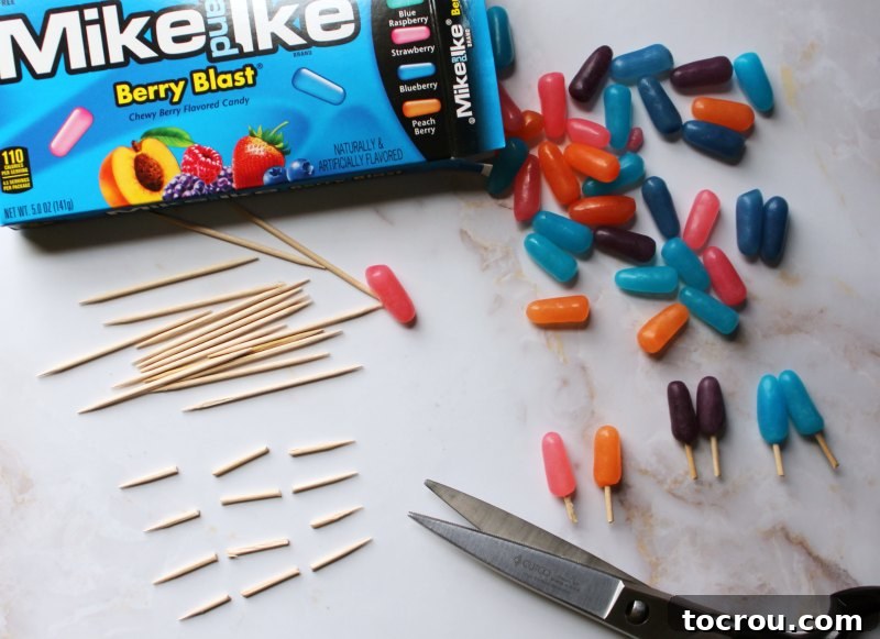 A box of Mike and Ike candies alongside several cut toothpicks, demonstrating how to create the small popsicle stick toppers.