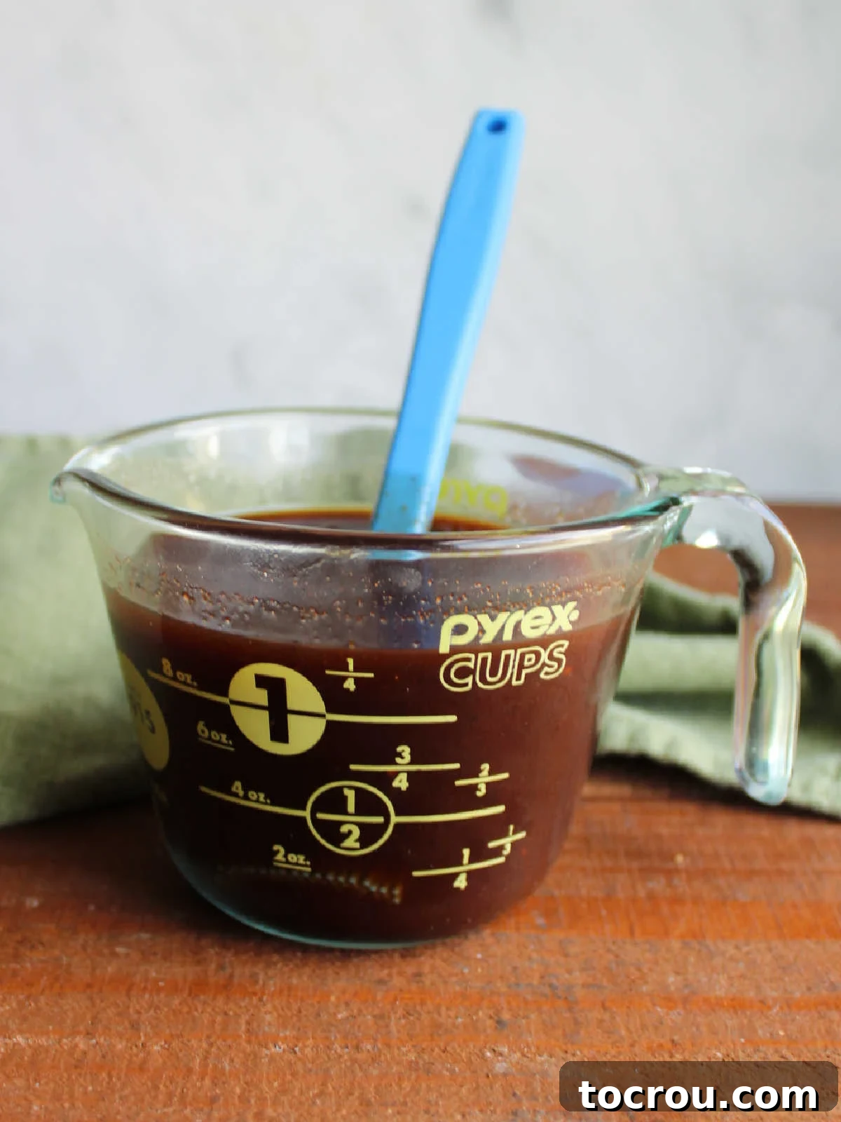 Smoky Perfection: Pellet Grill Pork Steaks 6 Measuring cup filled with bbq sauce that has been thinned out with apple juice and a silicone basting brush.