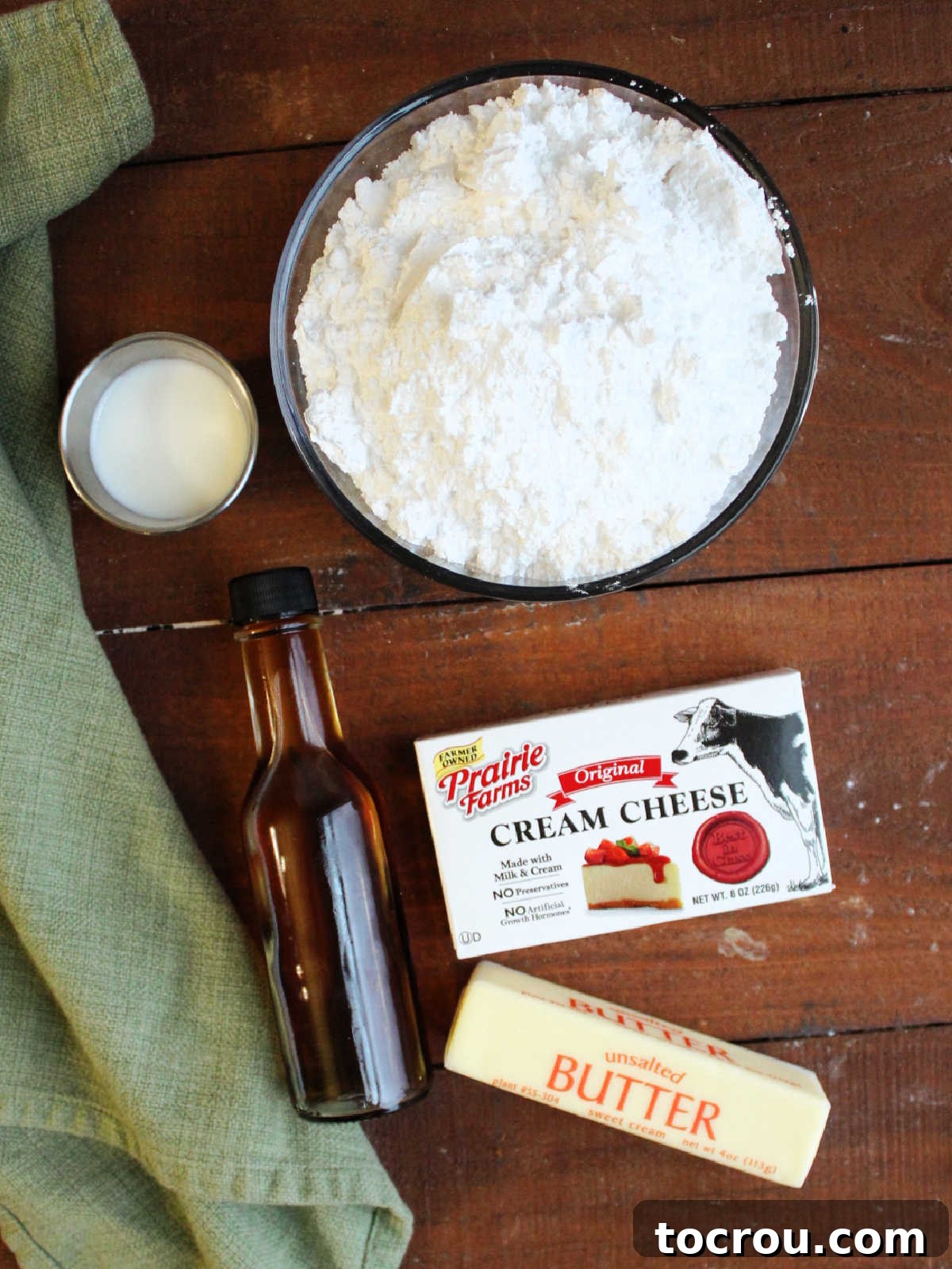 Ingredients for stable cream cheese frosting: cream cheese, butter, powdered sugar, vanilla extract, and milk laid out for preparation.