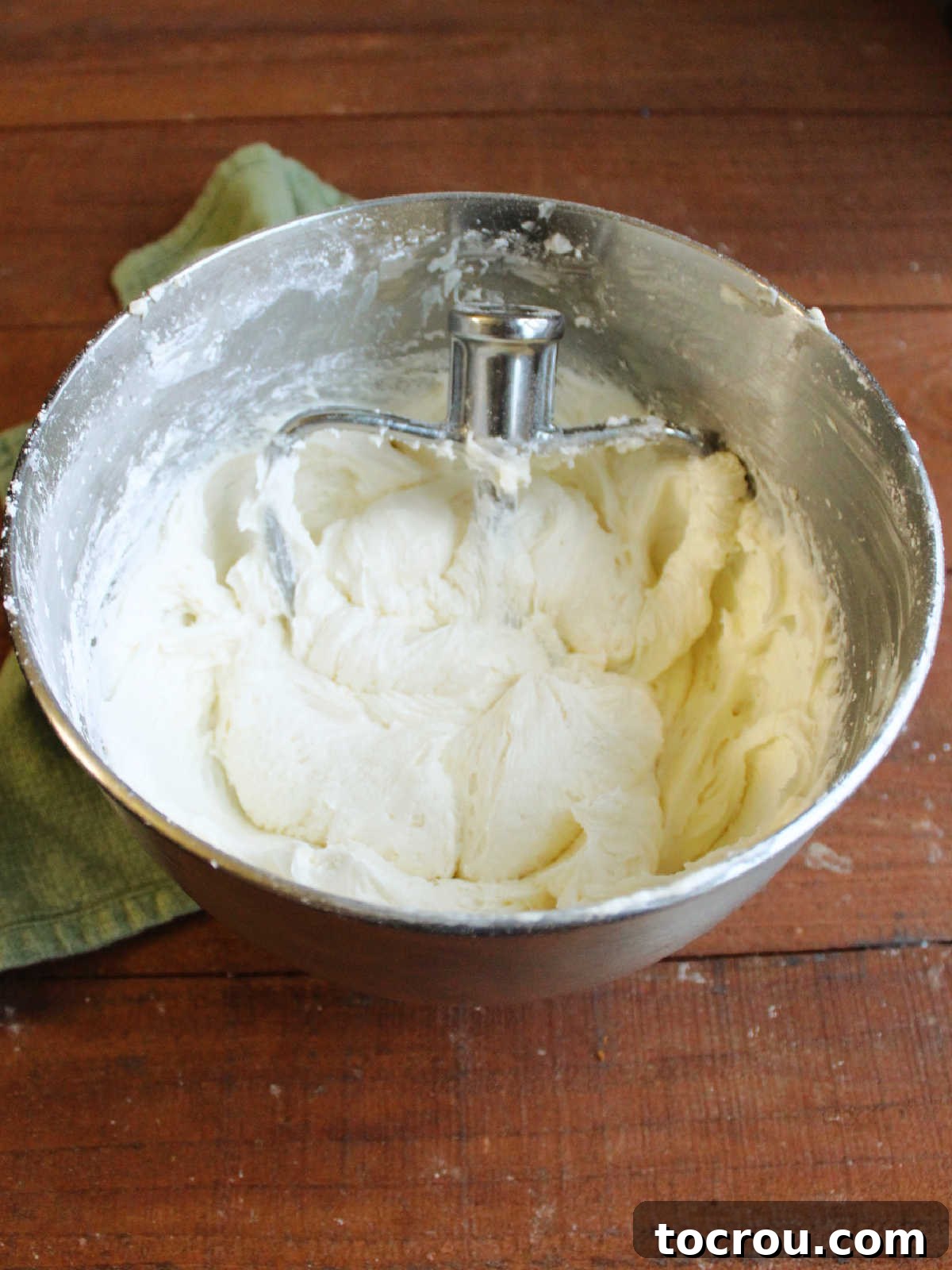 Large mixer bowl with a double batch of smooth, fluffy decorator's cream cheese frosting inside, ready for piping.