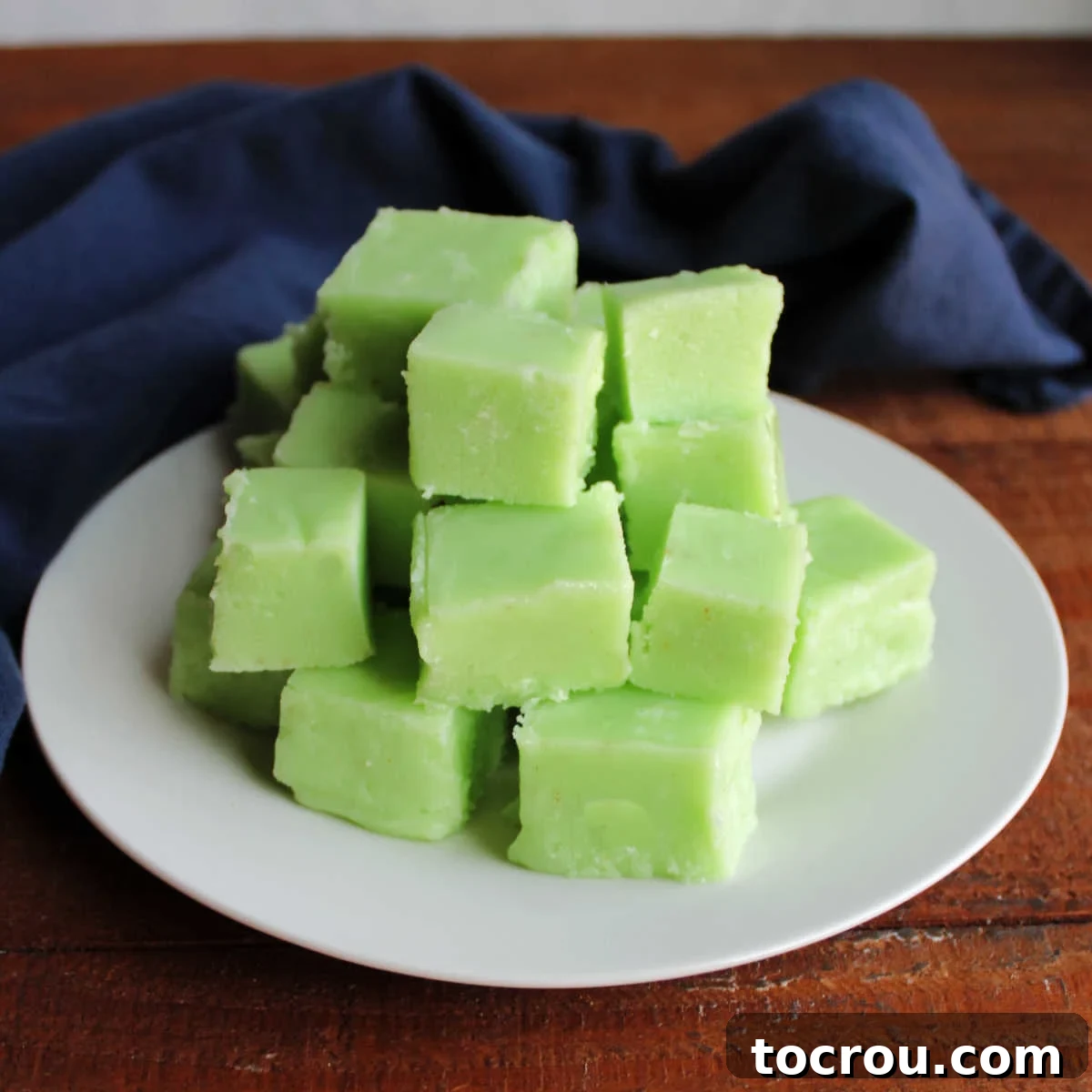 Plate of creamy light green colored lime jell-o fudge squares, ready to be eaten.