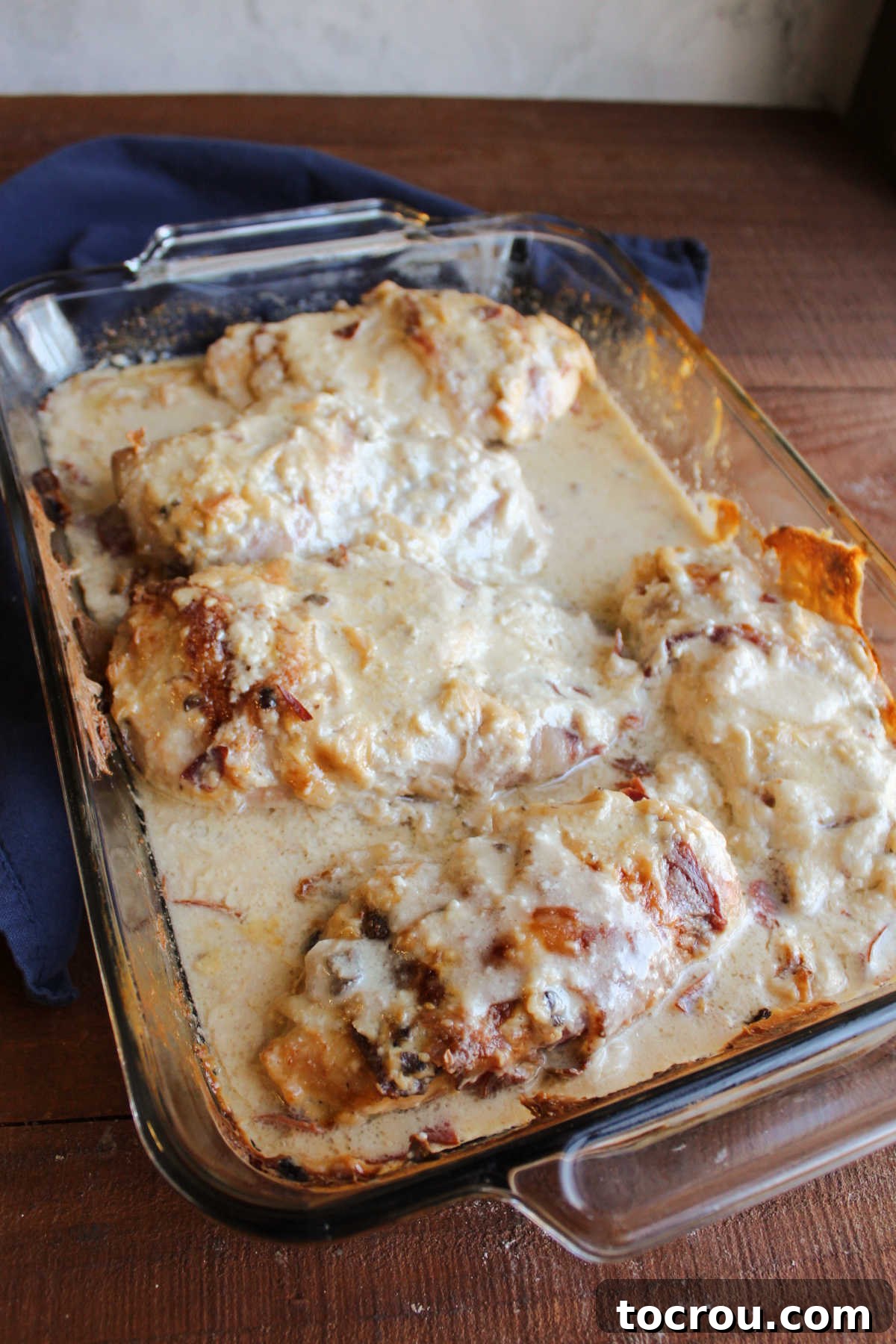 Pan of party chicken fresh from the oven showing how the sauce thinned out, the bacon crisped up and the chicken is cooked.