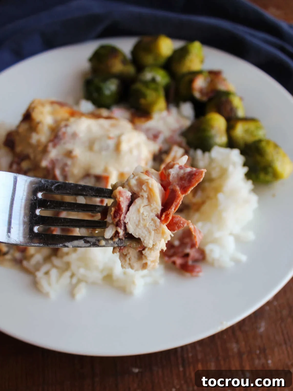 Bite of party chicken with dried beef and bacon on fork, ready to eat.