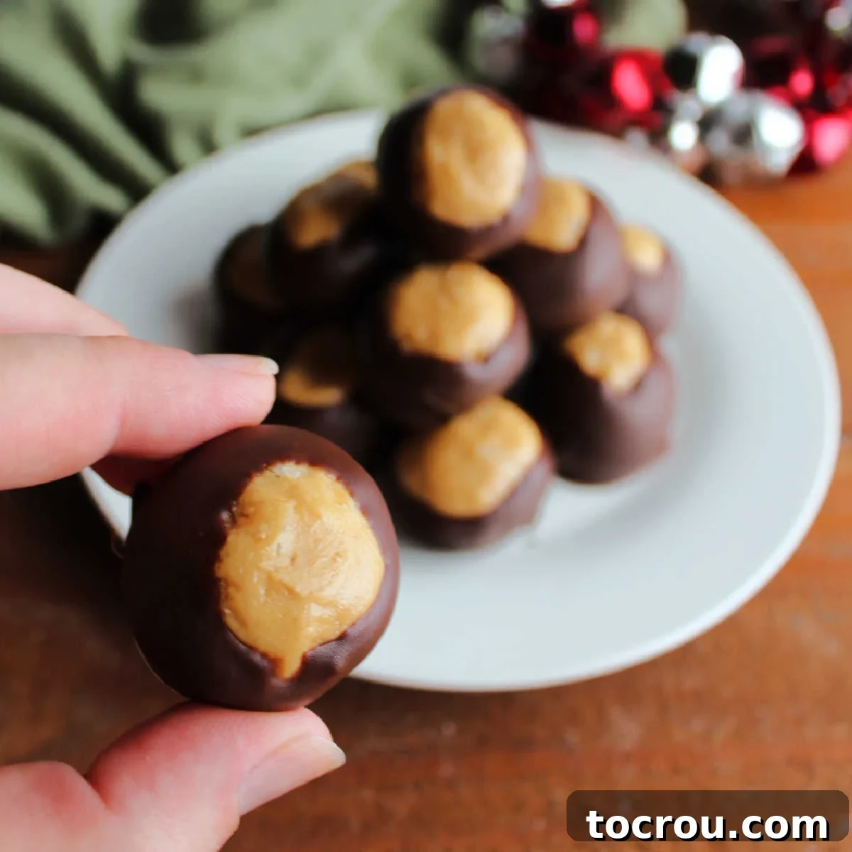 Rice Krispie Crunch Buckeyes 2 Hand holding crunchy peanut butter buckeye with dark chocolate coating.