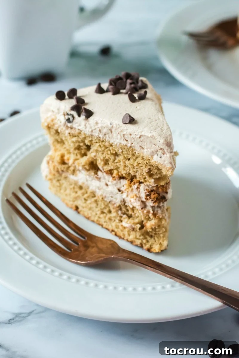 Perfect Slice of Coffee Cake A delectable slice of layered coffee and cream sponge cake on a white plate with a fork, ready to be enjoyed.