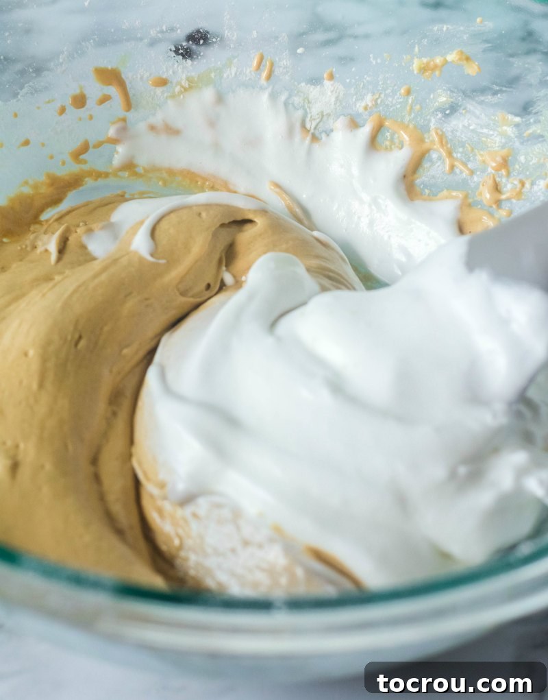 Folding Egg Whites into Coffee Batter Bowl of coffee cake batter with fluffy egg whites being gently folded in, creating a light and airy mixture.