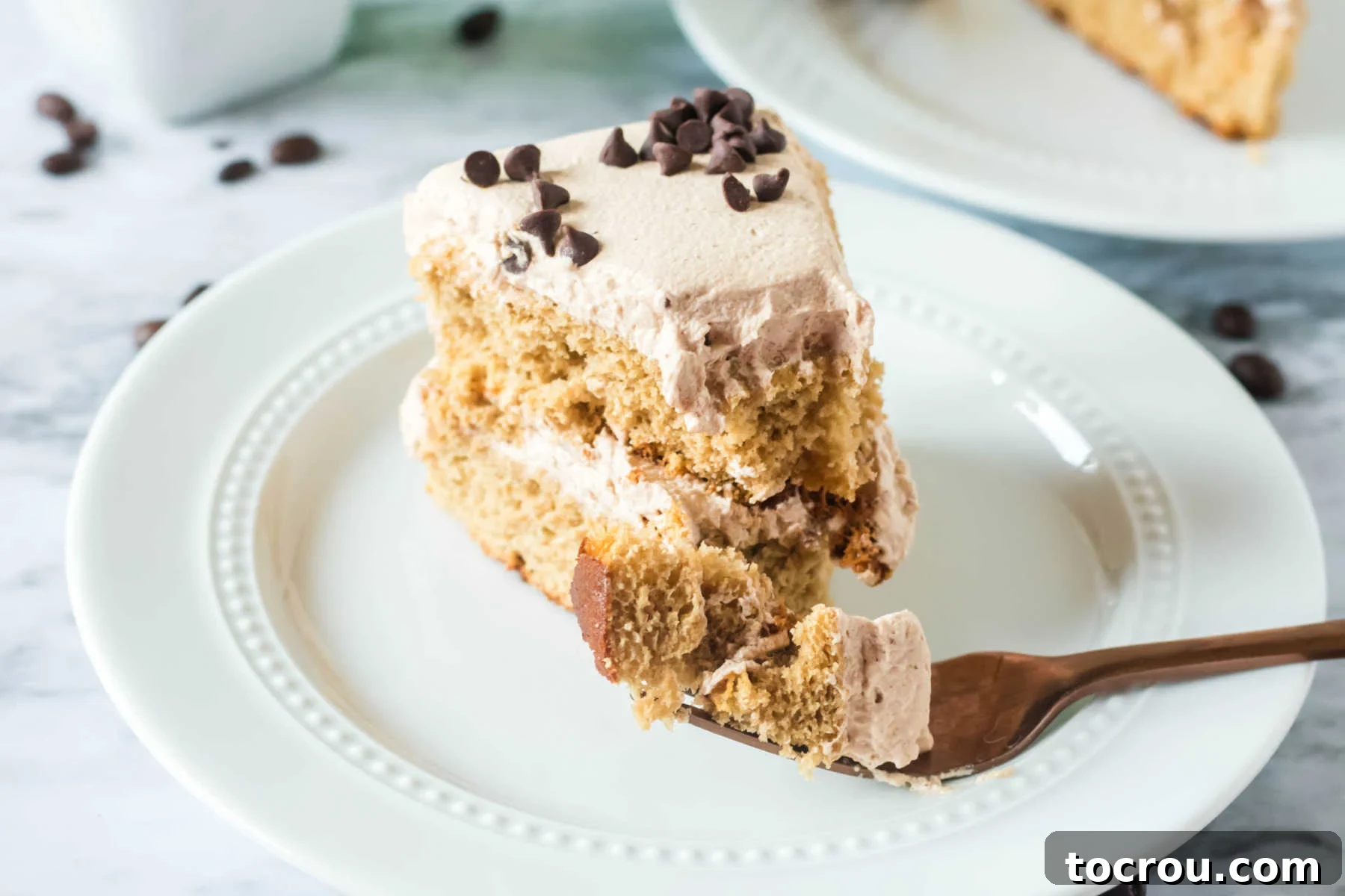 Ready to Enjoy A delightful piece of coffee and cream layer cake on a white plate, with a fork holding a perfect bite, inviting you to savor its flavors.