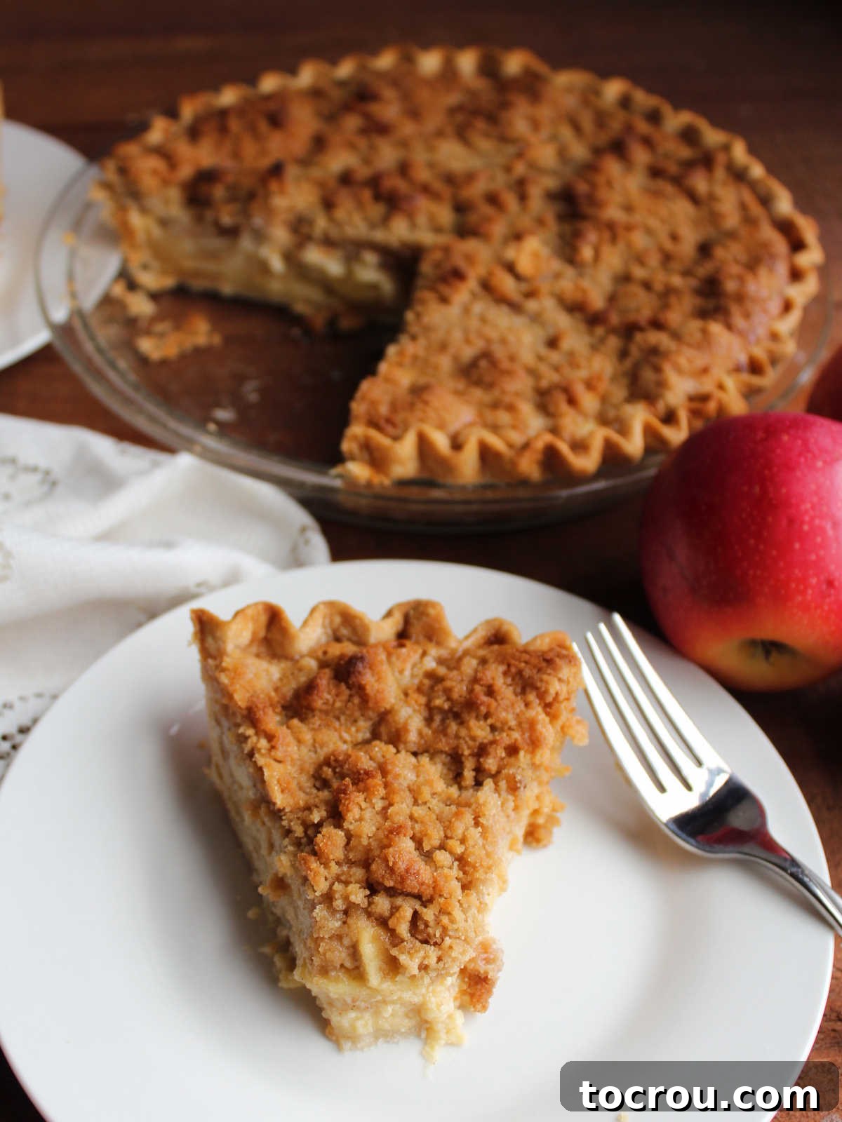 Apple Custard Crumble Pie 12 Piece of creamy apple pie on small plate with fork.