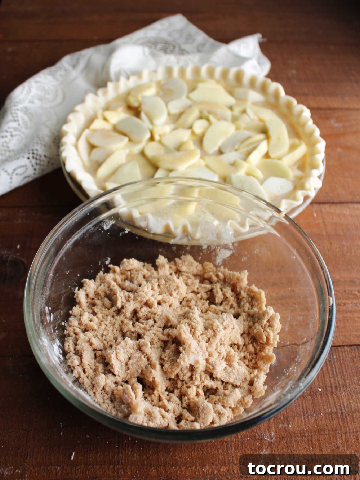 Apple Custard Crumble Pie 9 Bowl of brown sugar streusel mixture with small crumbs of butter coated in sugar and flour with pie in background.