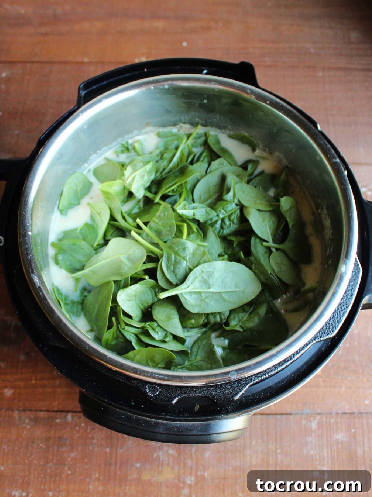 Adding baby spinach to Instant Pot.