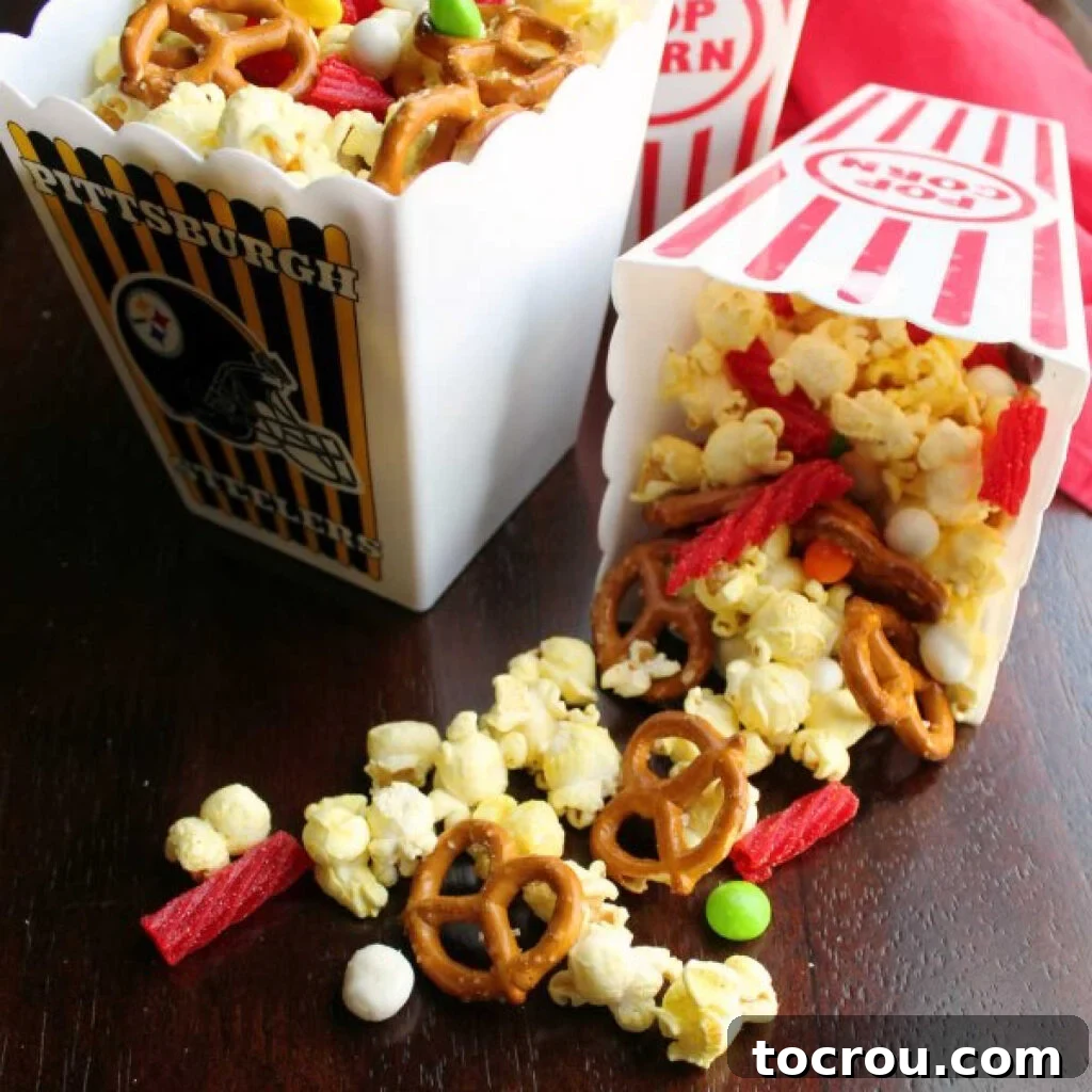 Small popcorn tubs filled with a vibrant movie theater snack mix featuring popcorn, pretzels, and various candies.