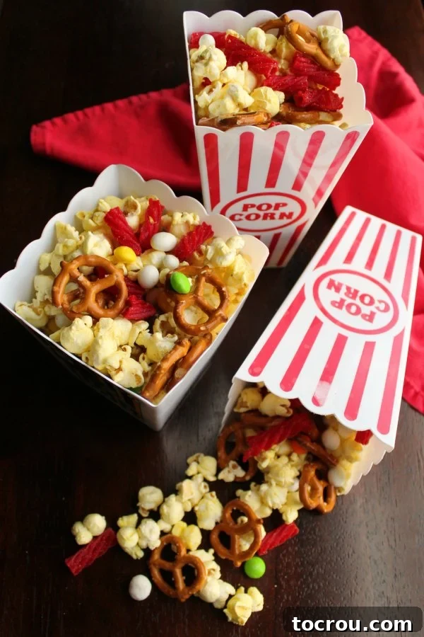 Red and white plastic popcorn containers filled with a vibrant snack mix, combining pretzels, popcorn, and colorful candies, ready for immediate enjoyment. 