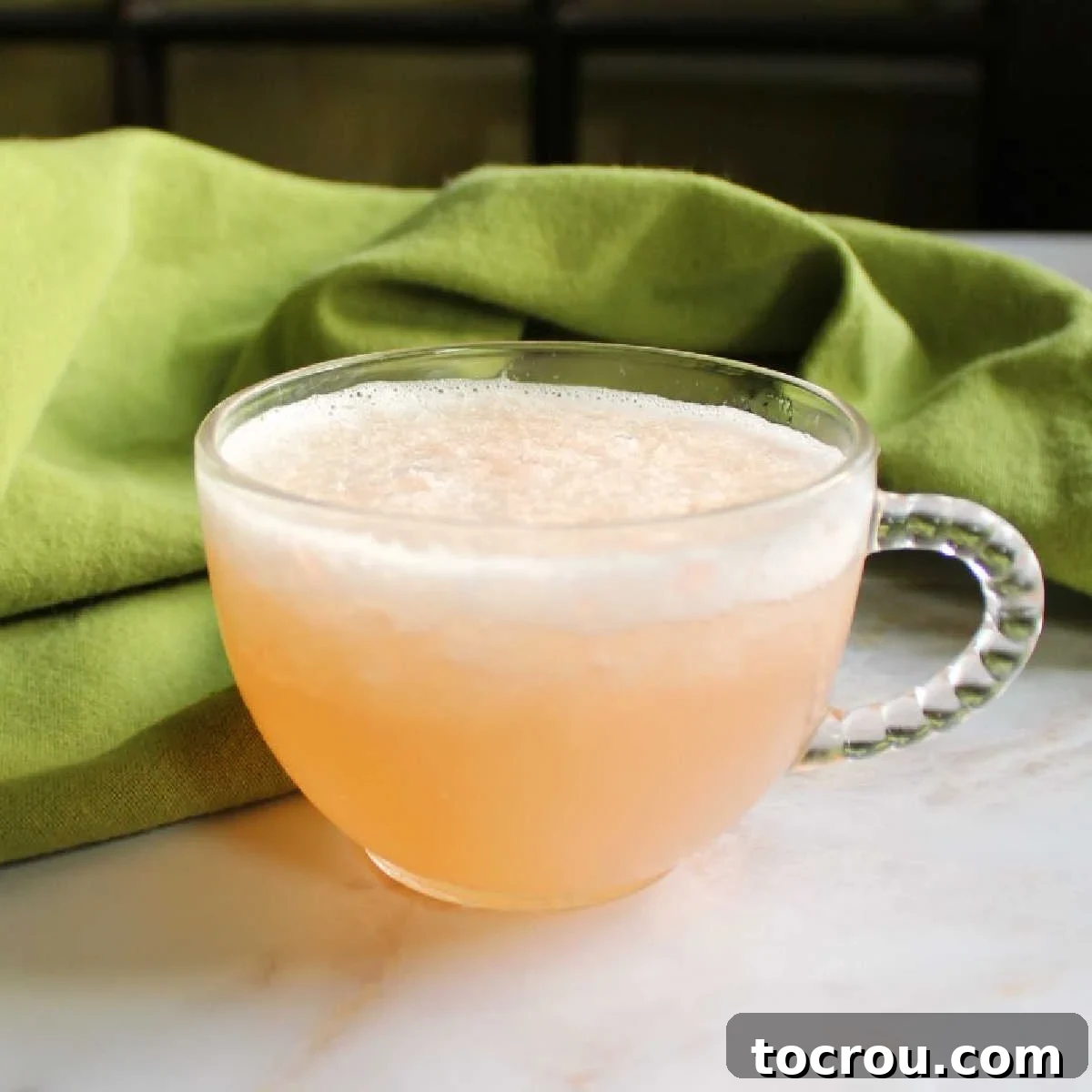 close up of a glass punch mug with slushy peach punch inside.