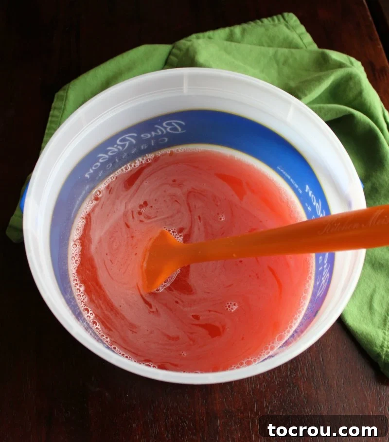 Peach jello and lemonade mixture in gallon container ready to be made into frozen punch.