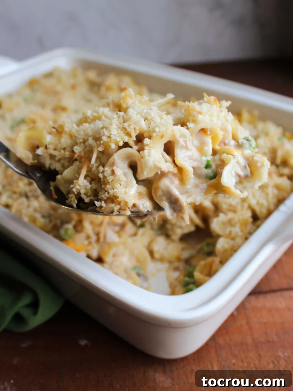 Hearty Tuna Noodle Casserole 10 Large serving spoon lifting a generous scoop of creamy tuna noodle casserole from the baking pan.