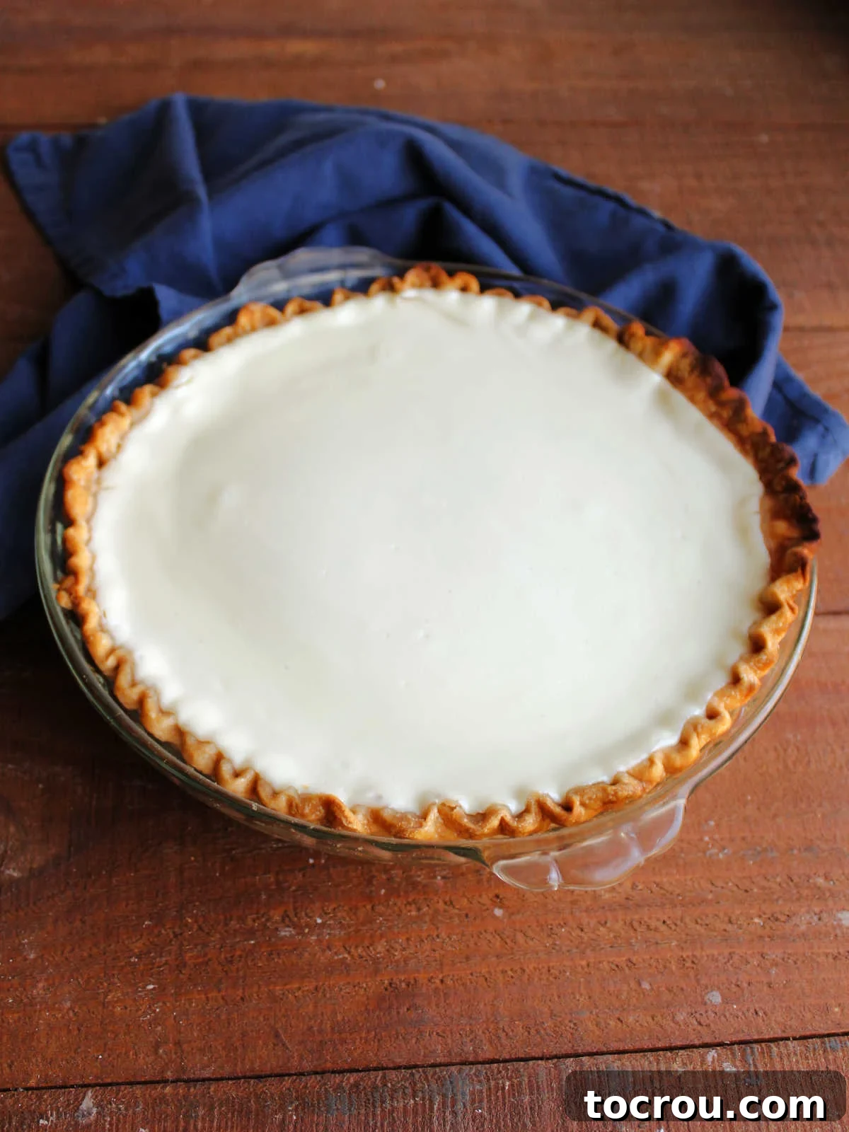 A beautifully baked and cooled layered pumpkin pie, featuring a perfectly smooth and evenly spread sour cream layer on top.