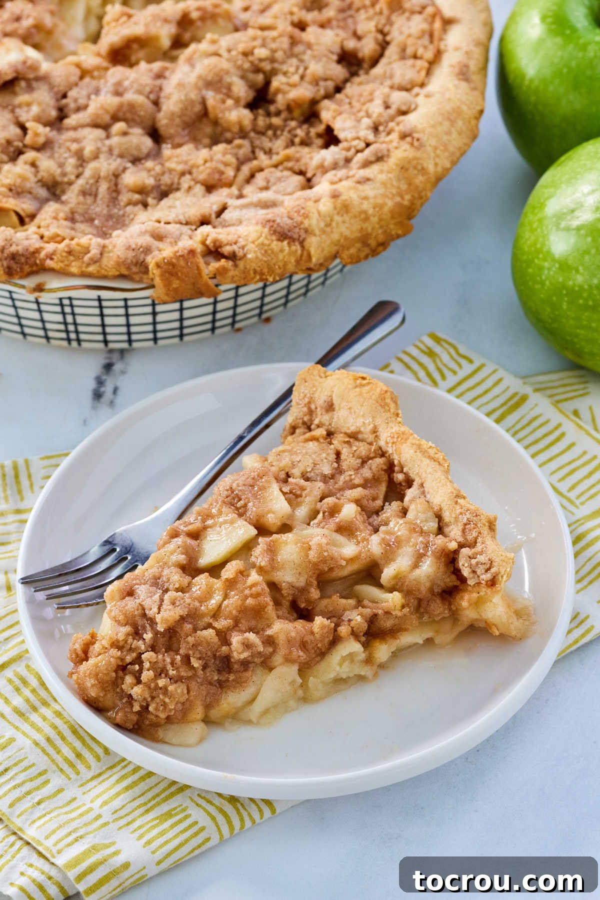 Piece of old fashioned Dutch apple pie on plate with fork, ready to eat. 