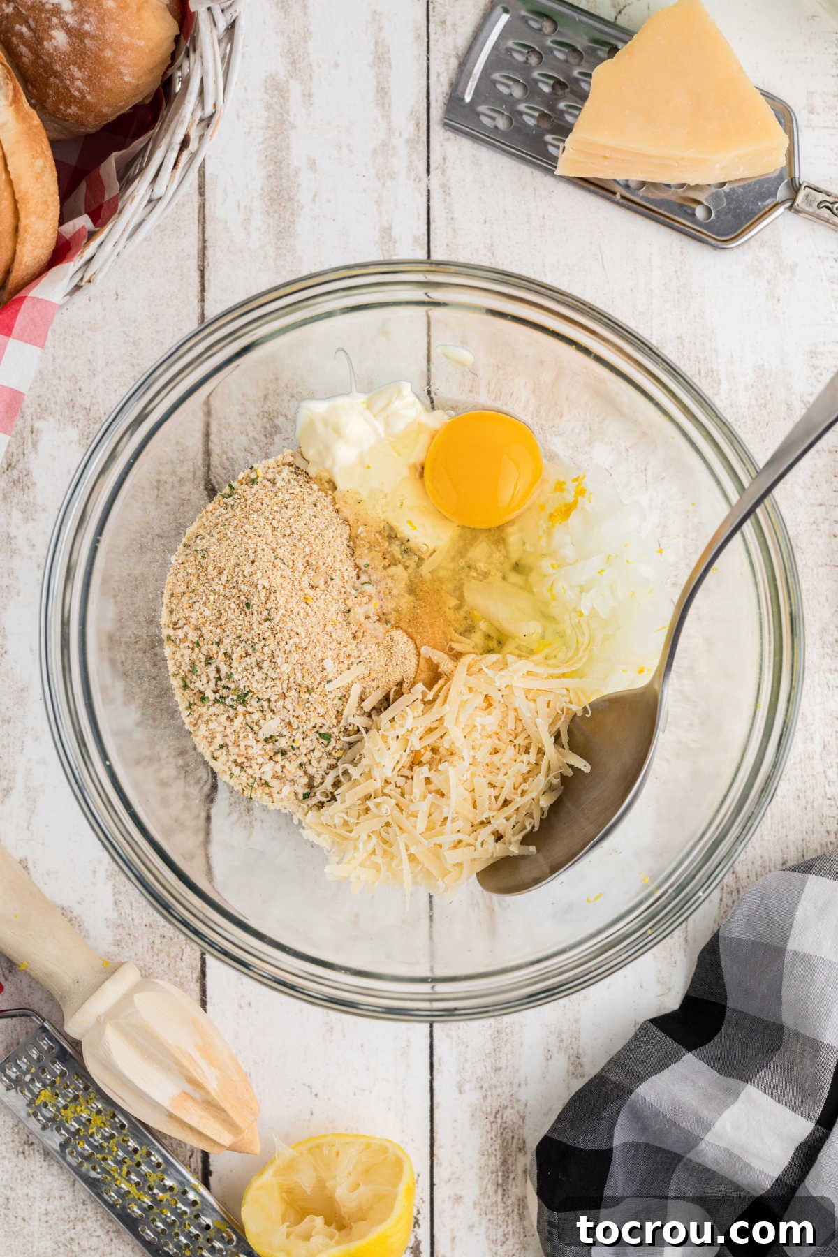 Mixing bowl filled with egg, mayonnaise, bread crumbs, cheese and seasonings ready to become the base for the tuna patties.