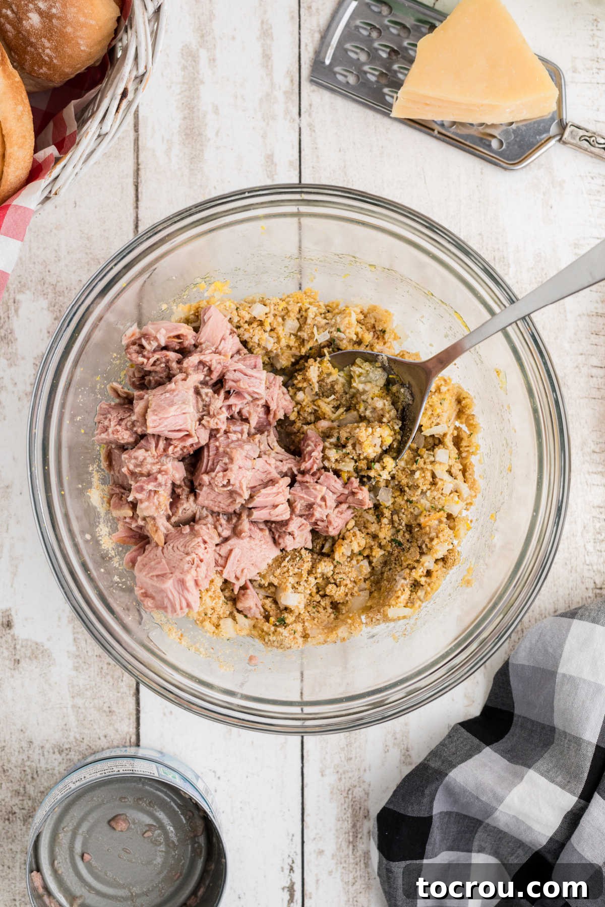 Adding drained flaked tuna to the mixing bowl to finish the mixture.