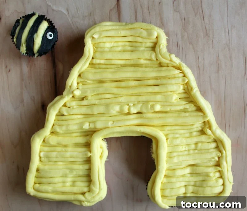 Sun-Kissed Lemon Honey Cream 4 A beautifully frosted beehive-shaped cupcake cake adorned with a small bee cupcake on top, showcasing the smooth honey lemon frosting.