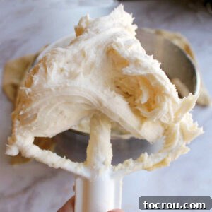 A mixer paddle filled with honey lemon buttercream frosting, ready to use for decorating.