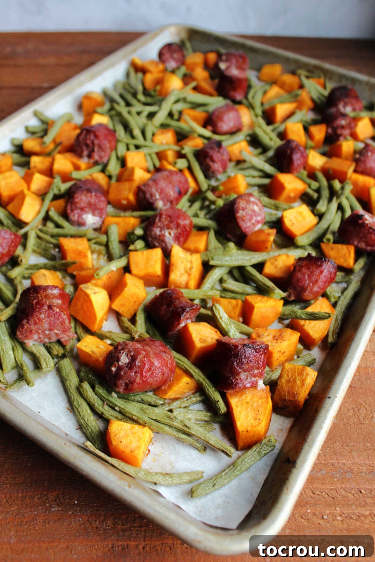 Roasted sausage, green beans and sweet potatoes on sheet pan, ready to be served.