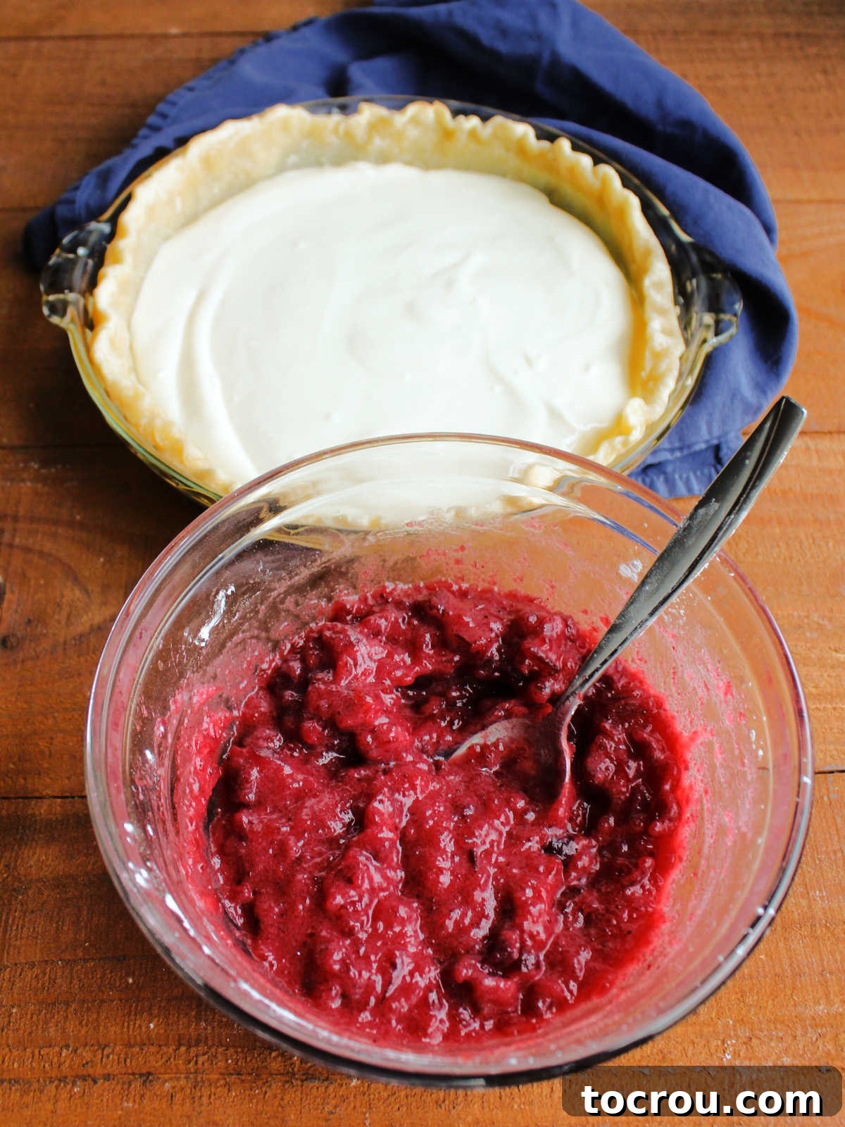 Buttery Crumb Cranberry Bliss 7 A mixing bowl containing a mixture of whole berry cranberry sauce, brown sugar, and cornstarch, perfectly prepared to be layered over the cream cheese mixture in the pie crust visible in the background.