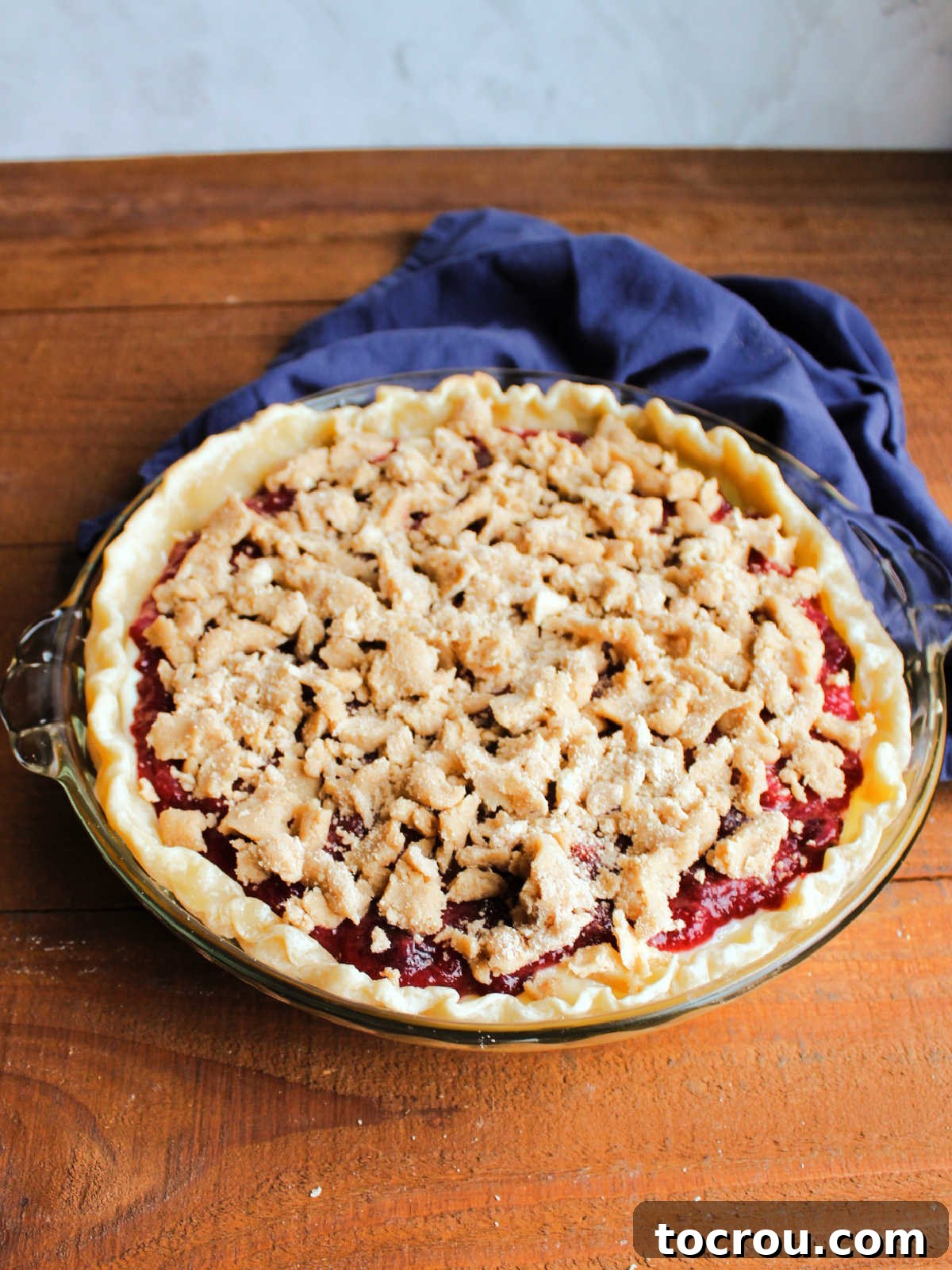 Buttery Crumb Cranberry Bliss 9 A beautifully assembled cranberry crumble pie, ready to be placed in the oven, with its distinct layers visible and a generous streusel topping.