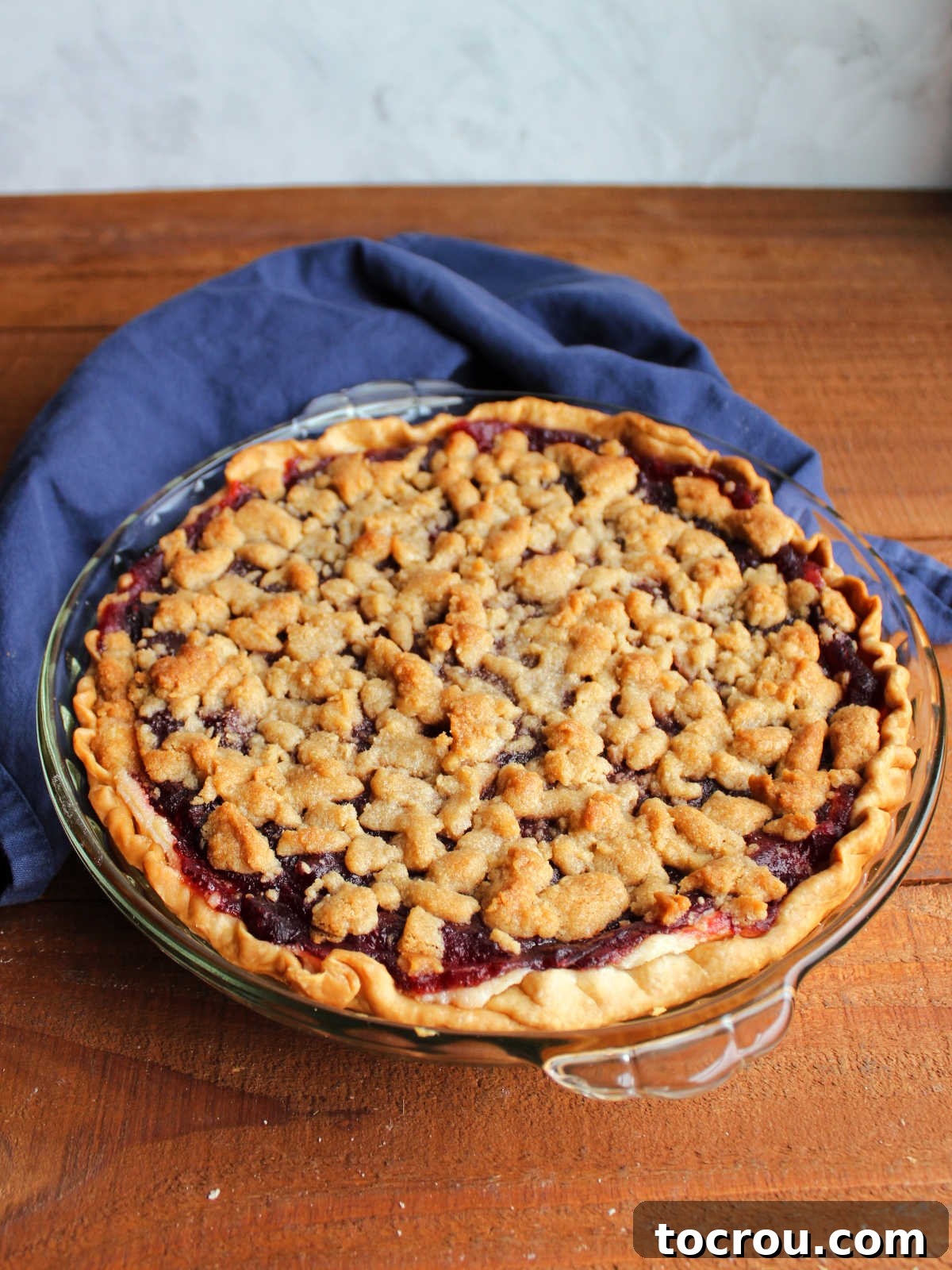 Buttery Crumb Cranberry Bliss 10 A perfectly baked cranberry crumble pie, boasting a rich golden-brown crumb topping and hints of the crimson cranberry layer peeking through, ready to be served.
