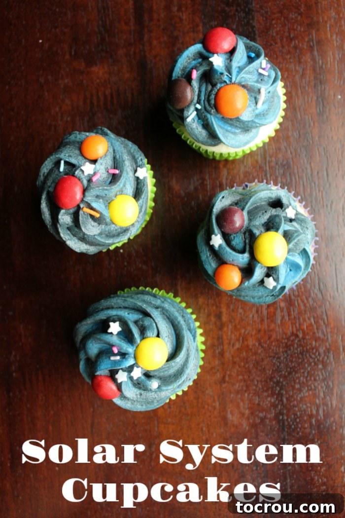 Delicious cupcakes adorned with dark, starry frosting, colorful candy planets, and sparkling star sprinkles.