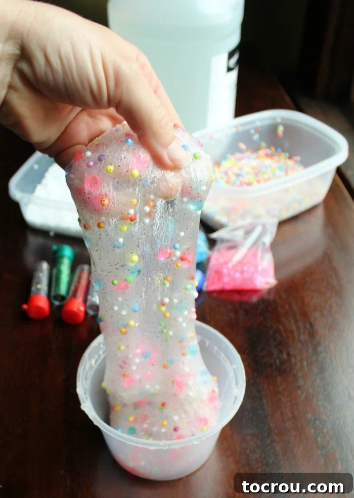 A vibrant batch of slime made with clear glue, baking soda, and contact solution, adorned with sparkling glitter and tiny styrofoam balls.