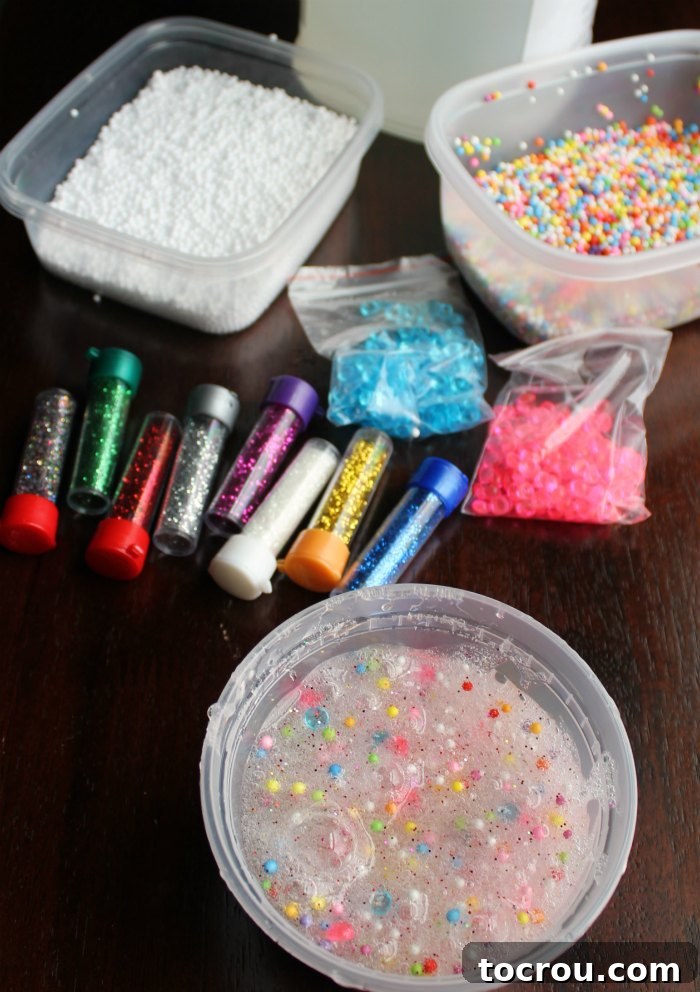 A tub of freshly made slime displayed next to an assortment of add-ins: tubes of glitter, colorful plastic beads, various foam balls, and a gallon container of clear glue.