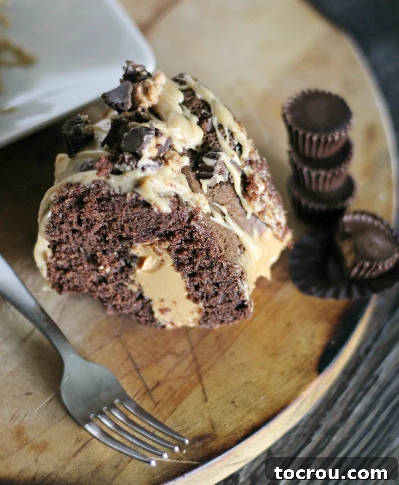 Enjoy the classic chocolate and peanut butter Reese's peanut butter cup combo in bundt cake form. This poke cake is easy to make and will leave a lasting impression! slice of chocolate bundt cake with peanut butter drizzle and filling next to stack of reese's peanut butter cups.