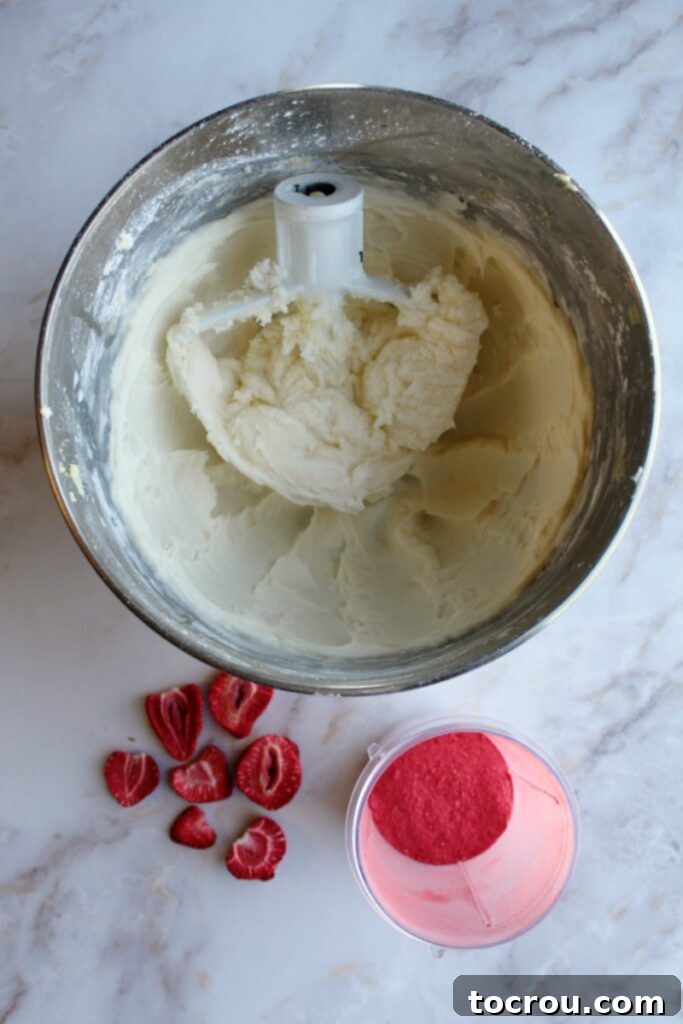 bowl of buttercream with freeze dried strawberries ready to go in.