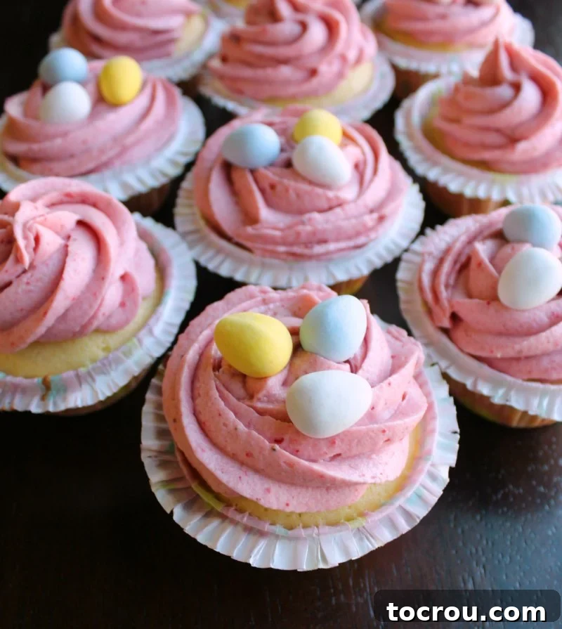 cupcakes with swirls of strawberry buttercream and mini chocolate eggs on top.