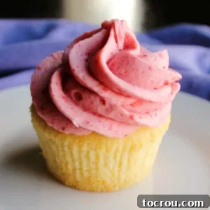 vanilla cupcake topped with swirl of pink strawberry buttercream.