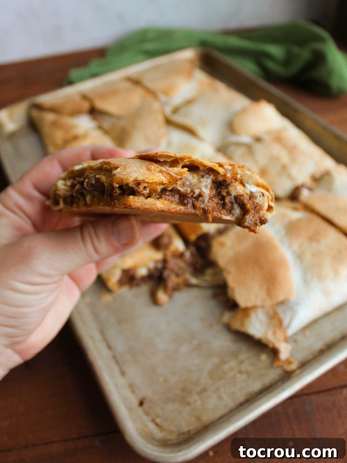 Sheet Pan Quesadilla Bake 3 Hand holding piece of sheet pan quesadilla showing gooey cheesy filling with ground venison.